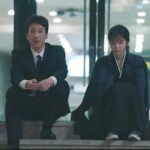 IU y el actor Lee Sun-kyun sentados juntos en unas escaleras durante una escena melancólica del drama coreano My Mister.
