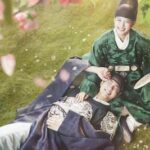 Los actores protagonistas de un drama histórico coreano visten hanbok tradicionales y descansan juntos en un campo de flores.